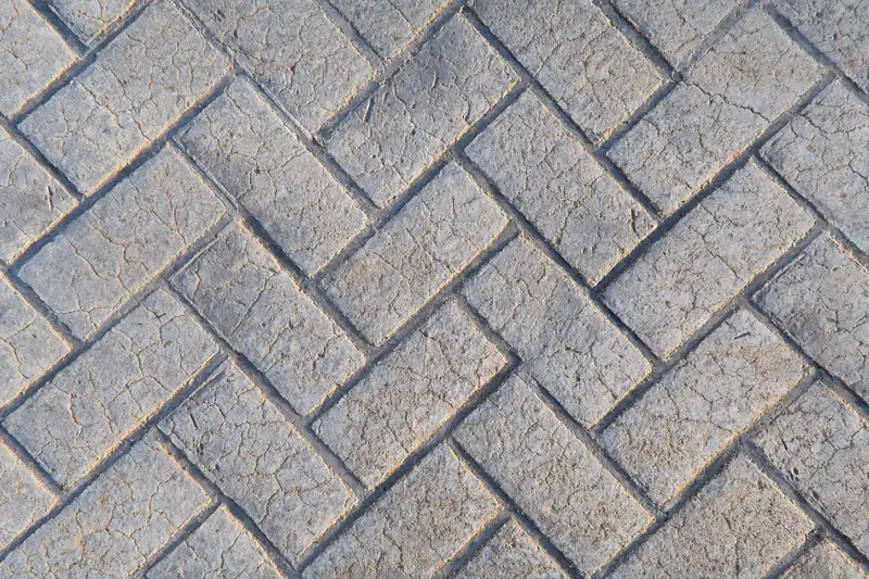 Detail of herringbone pattern stamped concrete with grey texture.