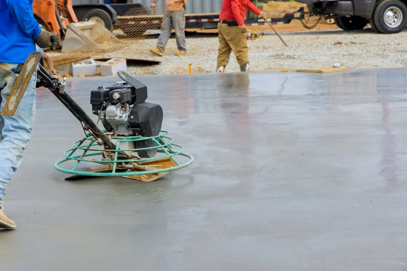 A professional contractor using a power trowel to finish concrete. A professional contractor using a power trowel to finish concrete.