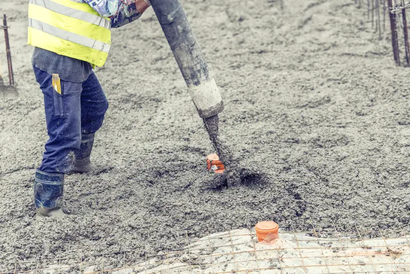 Pouring liquid concrete over steel mesh for a strong base. Pouring liquid concrete over steel mesh for a strong base.