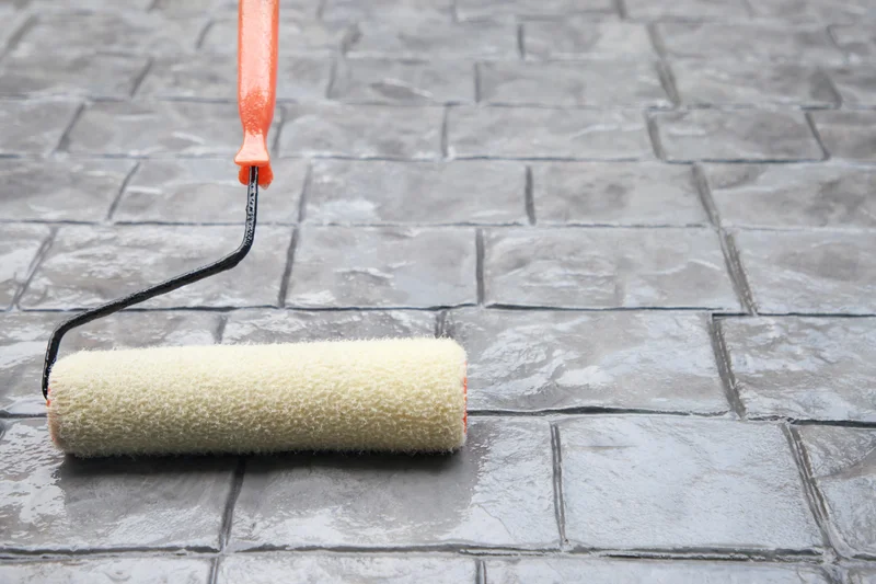 Sealing a stamped concrete driveway with a paint roller. Sealing a stamped concrete driveway with a paint roller.