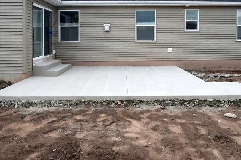 New concrete patio installation in the backyard of a modern residential home. New concrete patio installation in the backyard of a modern residential home.